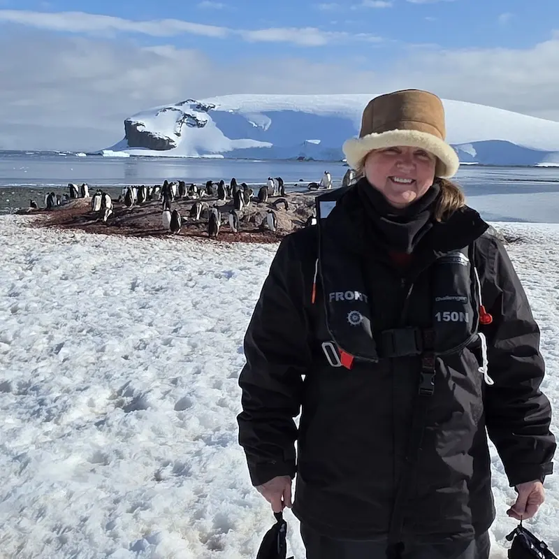 Visit the penguins in Antarctica in style Sandra Skelton with penguins behind in Antarctica