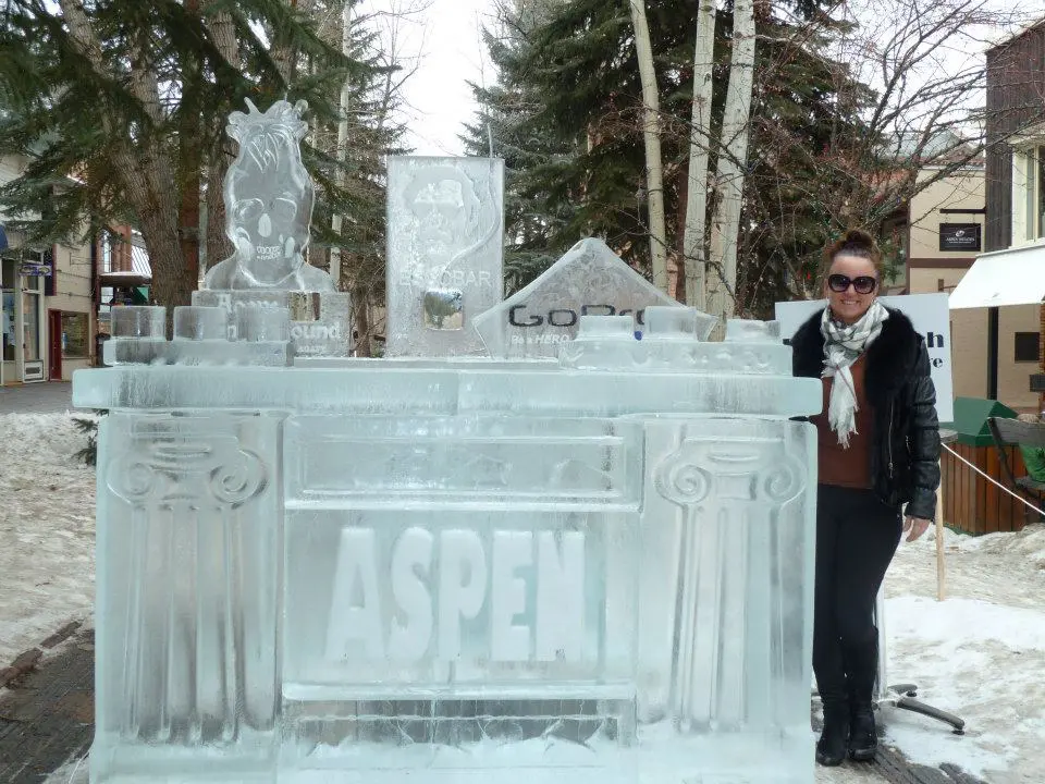 Stylish Aspen adventures await you Sandra standing beside a large ice sculpture sign of Aspen